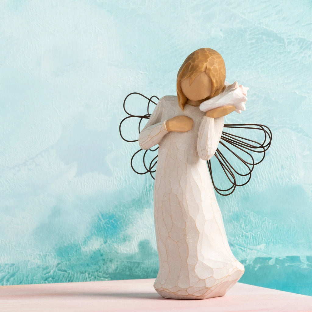 Willow Tree Thinking of You, 5.5”h hand-painted standing resin figure in cream dress with wire wings, holding pink conch shell to ear, in front of sea blue painting