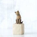 Golden cat figurine sitting on white rock