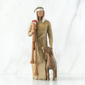 Wise man figurine standing in light brown attire with white headpiece, brown sheep at his feet