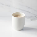 Filled scented candle with unglazed off-white tapered cylinder vessel, sentiment written in gold inside rim, plant-based wax blend, all-cotton wick.