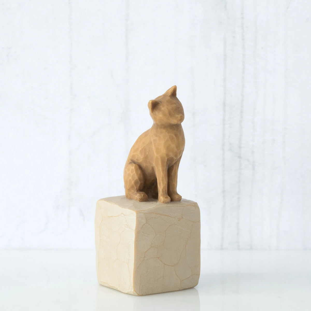 Golden cat figurine sitting on white rock