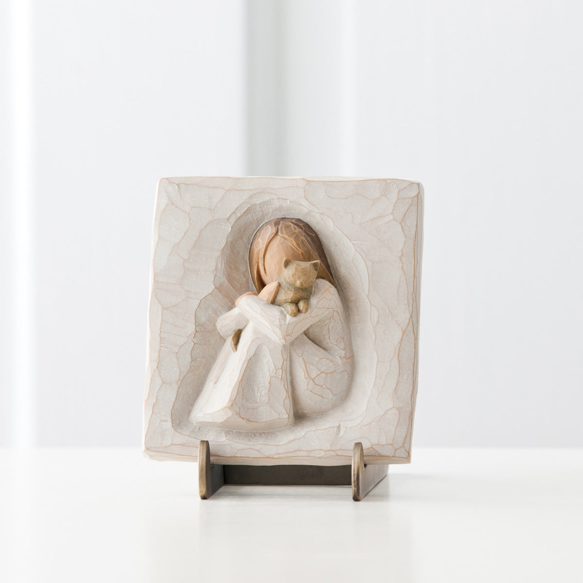 Close view of sqaure pendant with carved in girl figurine centered holding cat figurine
