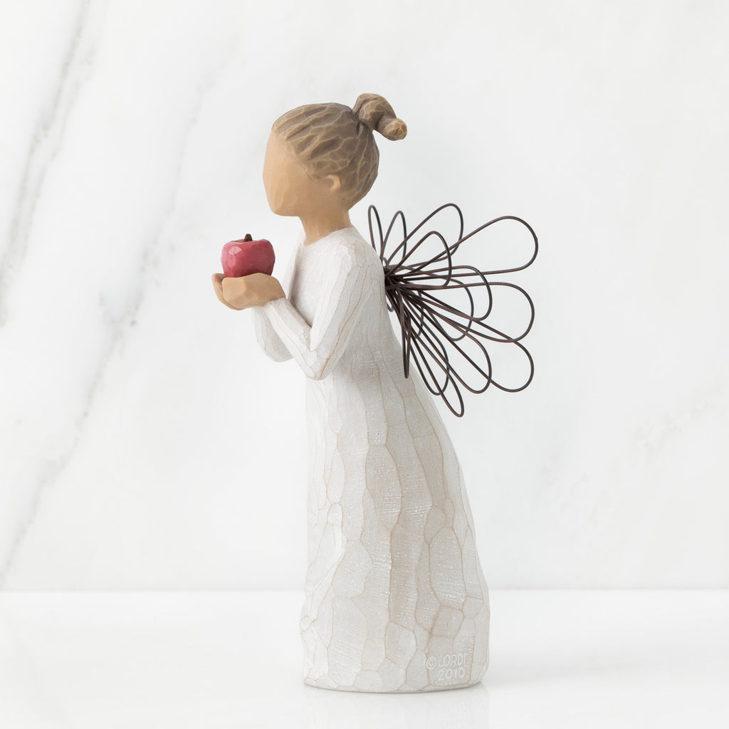 Right side view of angel with brown hair in high pony tail leaning forward and holding a red apple up to her face with both hands