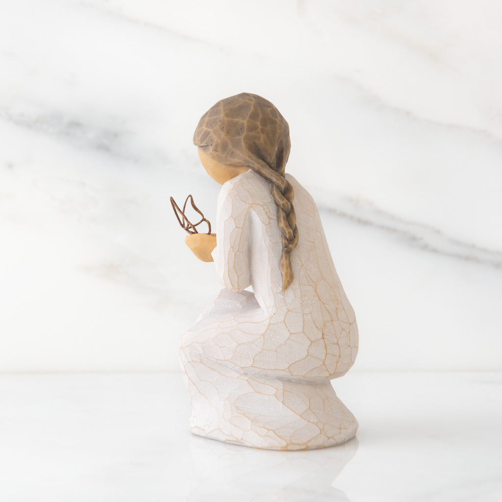 Left back view of kneeling female figure in cream dress, with wire butterfly on extended hands