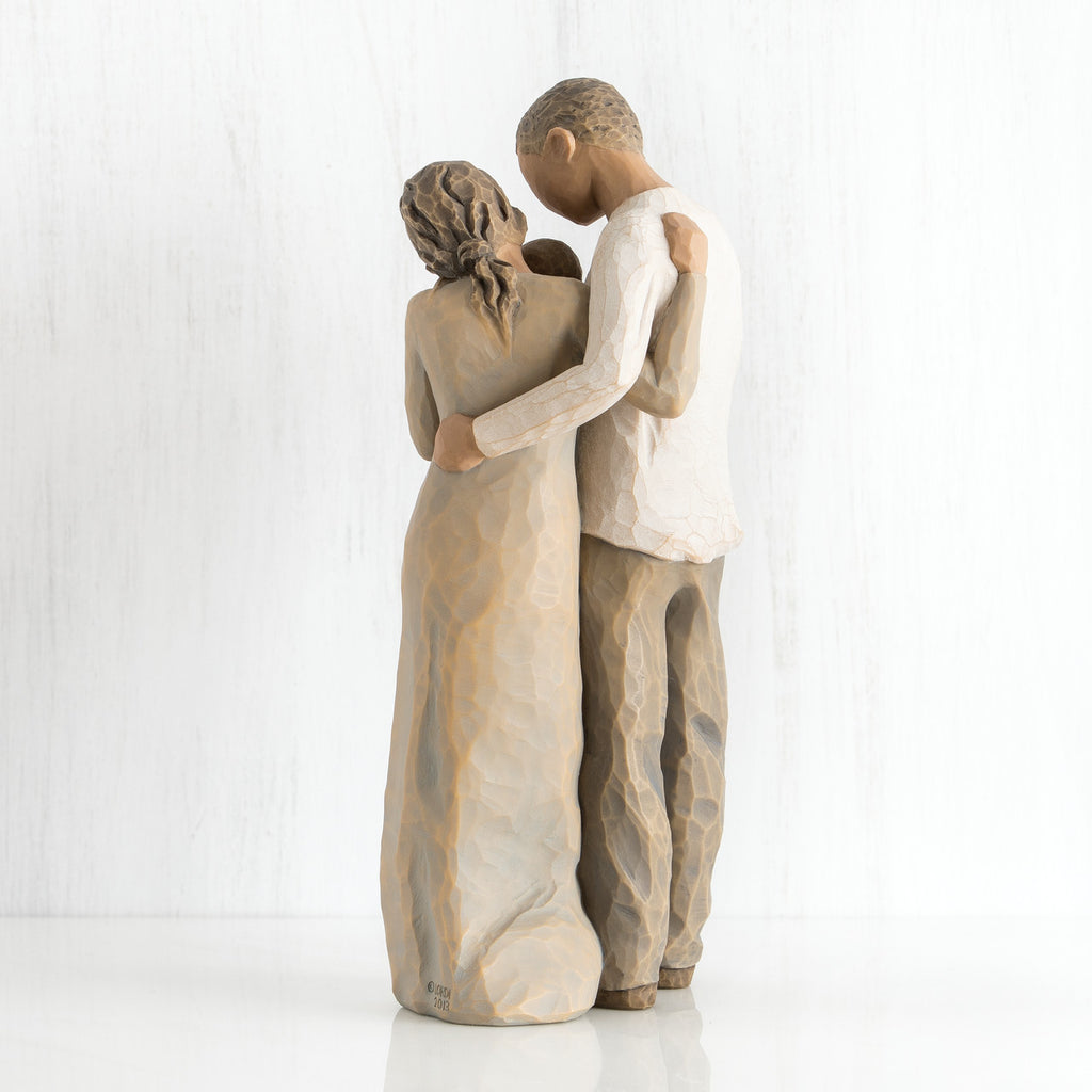 Back view of man and woman figurines hugging one another