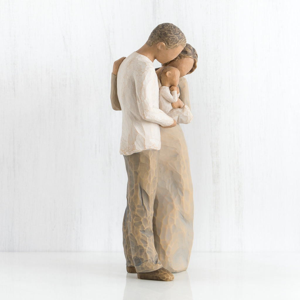 Side view of mother and father figurines holding a baby in their arms