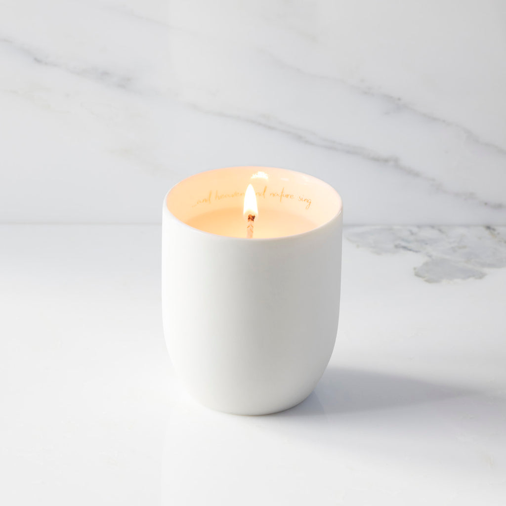 Lit filled scented candle with unglazed cream tapered cylinder vessel, sentiment written in gold inside rim, plant-based wax blend, all-cotton wick