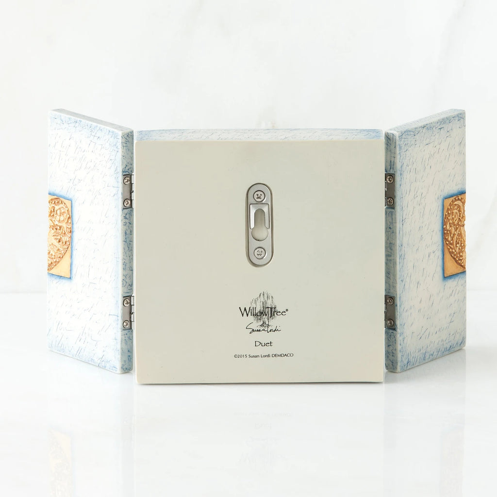 Back side of wooden white/blue book with silver key hole showing and willow tree printed in black