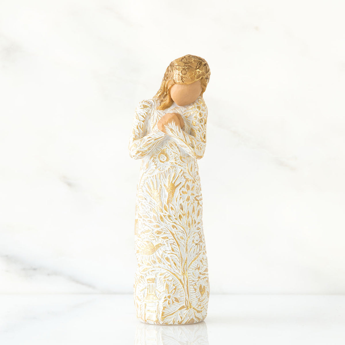 Faceless blonde woman figurine standing in white golden print dress clutching her hands to her chest