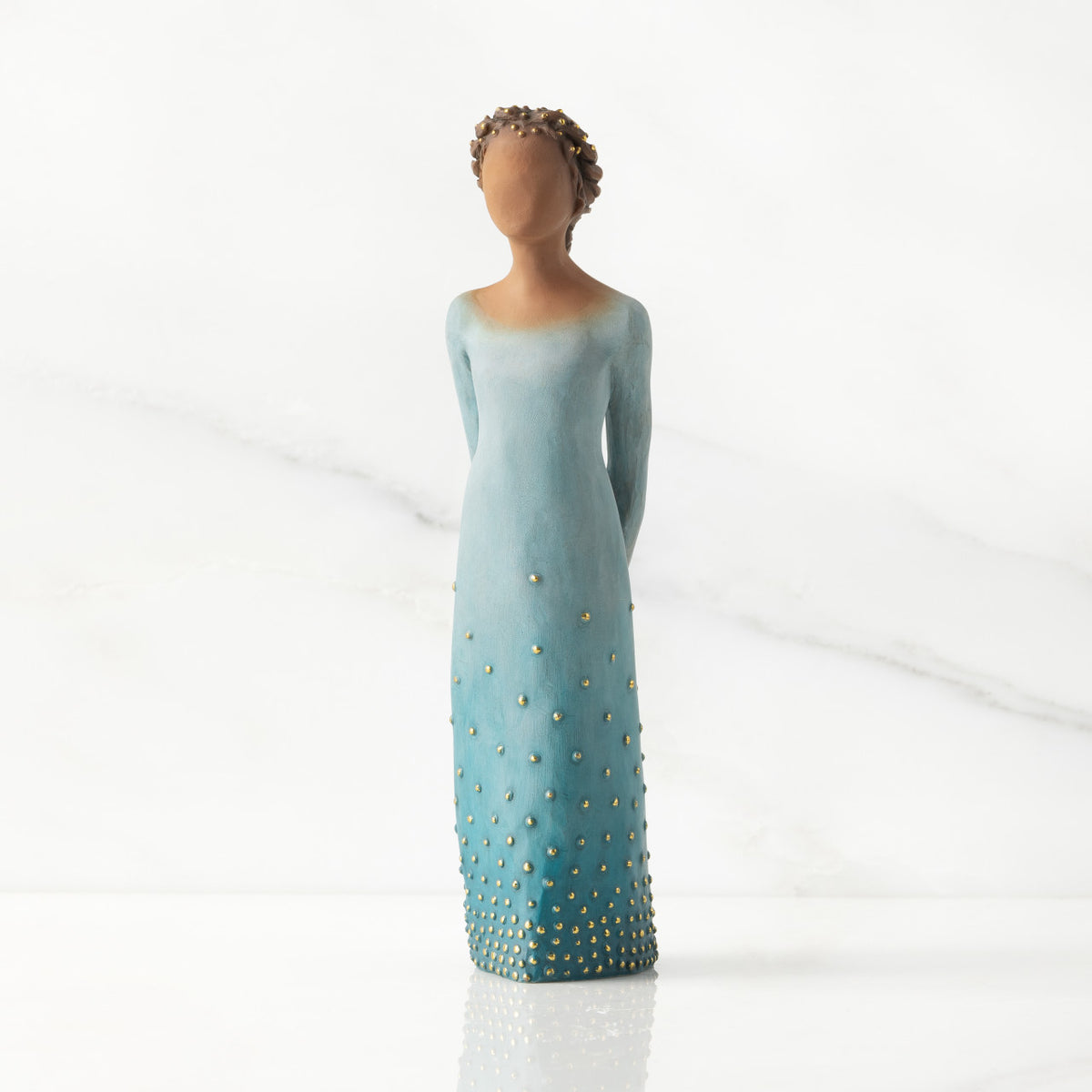 Facing front: Darker-skin figure, arms clasped behind back, hair and deep blue ombré garment dotted with gold leaf