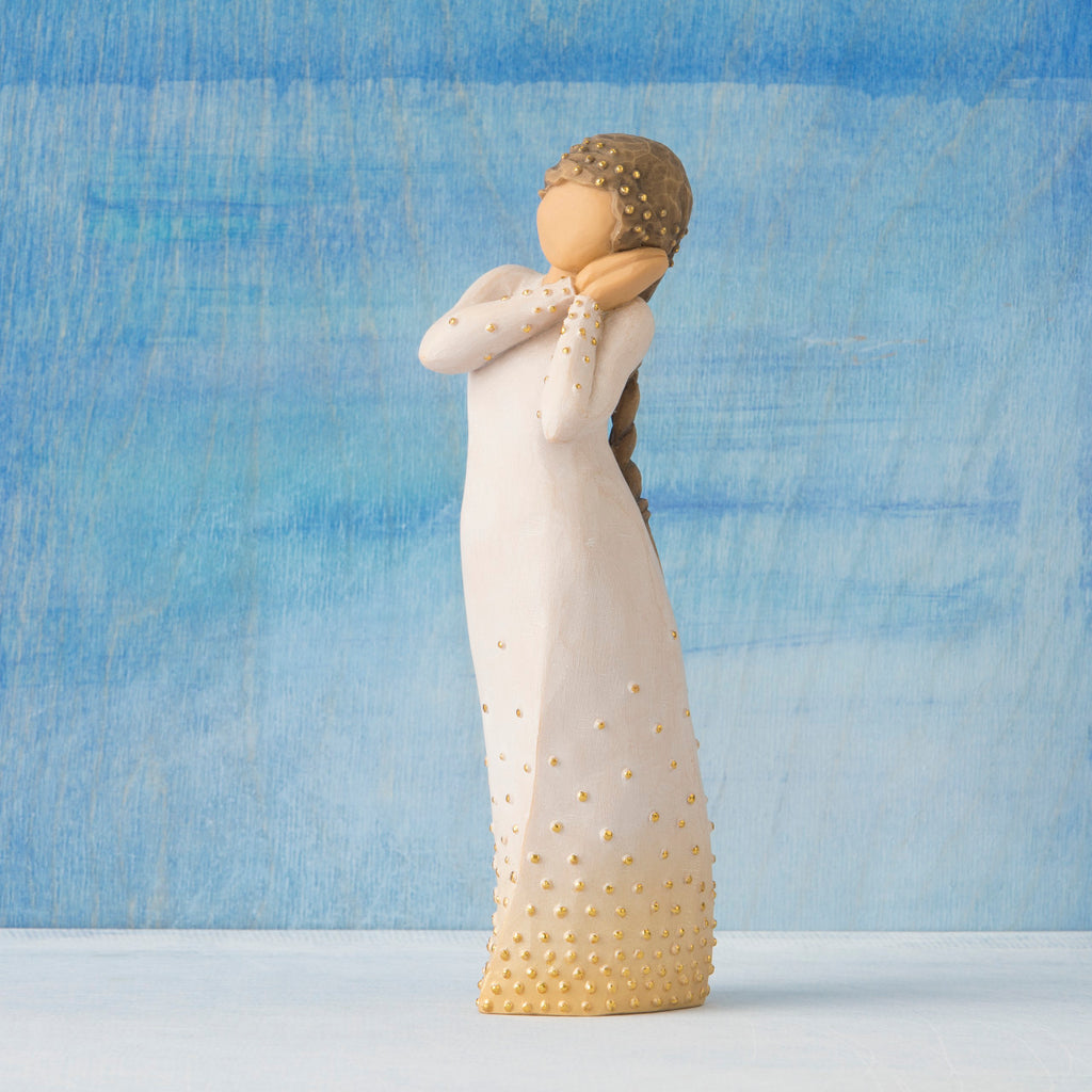 Front view, standing figure in cream dress, holding arms to face in wistful gesture. Hair and dress embellished with gold dots