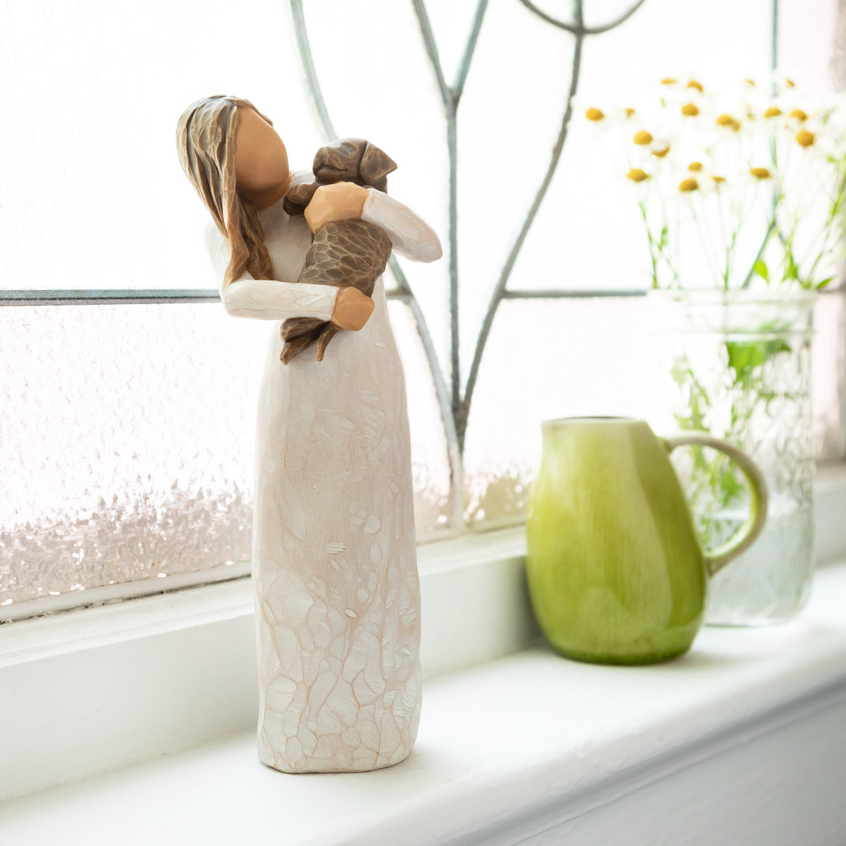Willow Tree Adorable You (dark dog), 7.5”h hand-painted standing resin figure in cream dress, holding puppy, on bright windowsill